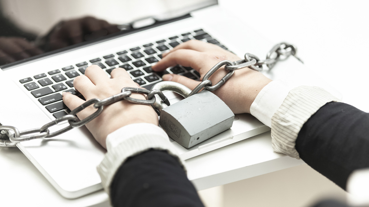 Closeup photo of woman locked in chain typing on laptop